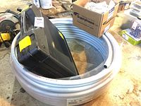 White coiled Viega PEX tubing and black plastic Viega tool case on concrete floor