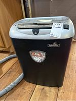 Front view of the black and silver Fellowes PS-14C shredder showing paper slot, power switch, and shredded paper in the window.