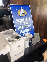 Photo showing Star Trek metal sign, two mugs, three metal medallions on stands, and pocket watch in foam packaging