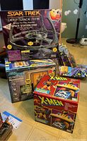 Wide shot showing all three items: Star Trek Deep Space Nine Space Station DS9, Star Trek Transporter, and X-Men Wolverine telephone all in original boxes.