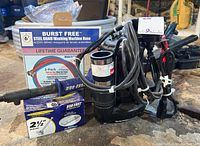 UtiliTech sump pump, Duo-Fast strike tool, Duo-Fast fasteners box, Burst Free washing machine hose box arranged on surface