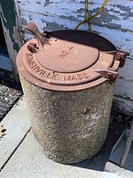 Side view showing the textured cement base and rusted metal top with the latch and the Somerville Mass No. 4 imprint.