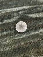 Top-down view of the rose quartz gemstone showing the round faceted cut and pink color.