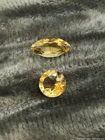 Photo showing top view of marquise cut citrine and round cut citrine on textured fabric