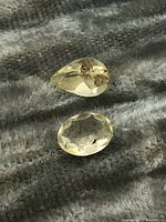 Two faceted Madagascar citrine gemstones on a textured surface.