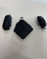 Photo showing 3 black lava rock pendants with sterling silver bails on white background