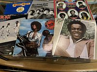 Seven vinyl record album covers including Barry White, Commodores, 5th Dimension, Archie Bell & The Drells, The Brothers Johnson, Lou Rawls with signs of wear.