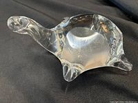 Clear blown glass turtle figurine shown from side angle, highlighting smooth, rounded body and protruding head and legs.