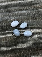 Four blue opal cabochon gemstones placed on a textured fabric surface, showing color and shape details.