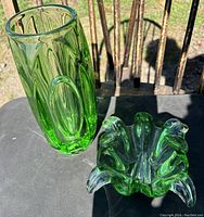 Photo showing both green glass vase and ruffled candy bowl on dark surface in sunlight.