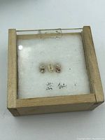 Top view of three miniature Japanese Kokeshi dolls displayed inside a wooden frame with glass top for size context.