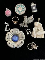 Top view photo of various sterling silver vintage jewelry items arranged on black background showing detailed designs and gem inlays.