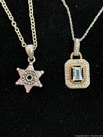 Two sterling silver necklaces with gemstone pendants displayed on black background