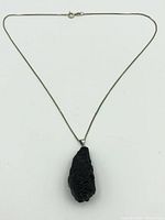 Full view of the tektite pendant and sterling silver chain laid flat showing the chain's length and pendant size.