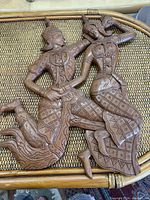 Front view of the carved wooden Tibetan wall plaque showing two figures in traditional dress and dynamic poses.