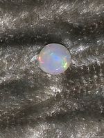 White opal cabochon centered on gray fabric background