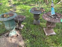 All four urn planters grouped on lawn showing two green-patina and two rust finish pieces