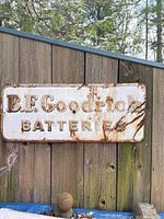 Full front view of sign mounted against wood fence showing overall design and condition