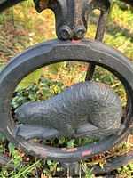 Close-up of cast iron beaver figure within circular medallion on the fence piece showing detailed texture and wear.