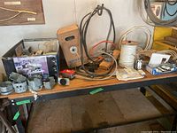 Overview of electrical items on a table including metal electrical boxes, wire spools, outlet receptacles, switches, and various cables and connectors.