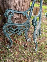 Photo showing close-up of one cast iron bench side armrest with lion head detail and curled feet