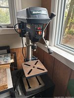 Front view of Mastercraft drill press showing adjustable work table, spindle and control handles.