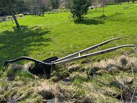 Side view of the Peter Hamilton No. 21 walking plow placed outdoors on grass and dried patches.