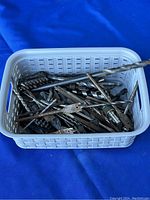 White plastic basket filled with numerous assorted drill bits and accessories.