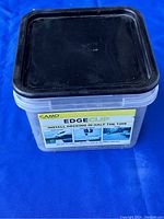 Plastic container with black lid labeled CAMO Edge Clip showing product branding and usage instructions.