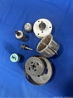 Set of 8 concrete hole saw bits arranged on a blue cloth background showing various sizes and conditions, some rusted, some silver metal, one with turquoise casing.