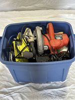 Blue plastic bin filled with power tools including a Black & Decker circular saw and a Ryobi belt sander.