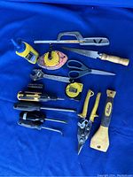 Photo of 15 assorted hand tools arranged on blue cloth.