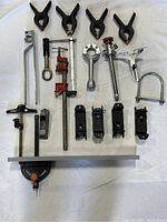 Overview of 19 pieces construction standard tools including large spring clamps, pipe cutter, adjustable wrench, quick-grip clamps, and other metal hand tools.
