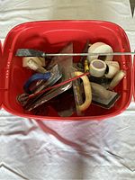 Red plastic box containing assorted plaster and stucco construction tools viewed from top