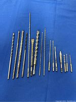 Set of 16 hammer drill bits and chisels laid out on blue background