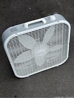 Front view of white square Lasko box fan showing grille and logo.