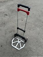 Full view of the trolley standing upright on a paved surface showing the extended handle and folded base plate.