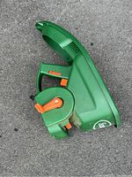 Top view of green plastic Scotts handheld fertilizer spreader showing handle, orange adjustment lever, and seed guard compartment.