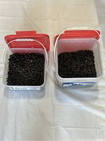 Two plastic boxes filled with black coated screws, one box is labeled as containing 6x1 1/4 drywall screws and the other 8x1 3/4 floor screws.