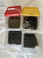 Four plastic containers with different screws, varying in color and size, some with metal brackets visible.