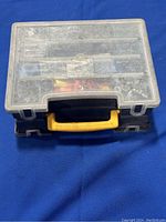Closed plastic tool storage box with yellow handle on blue fabric background