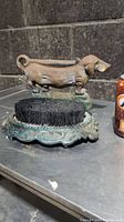 Cast iron dachshund boot scrub with a stiff black bristle brush on a decorative base.