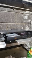 Photo showing Denon DCD-590 CD player with disc tray open and disc inside. Display and buttons visible.