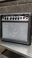 Front angled view of black guitar amplifier showing control knobs and metal grille