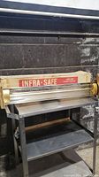 Photo shows the Infra-Safe heater front view with original box in background, heater placed on metal cart.