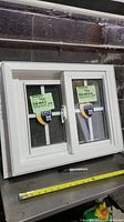 Full view of small white vinyl window with labels and sliding glass panes