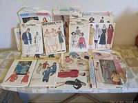 Lot of 12 vintage sewing patterns displayed on a flat surface including Vogue, Butterick, and McCall's brands with various illustrated designs.