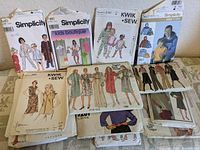 Photo showing a group of seven vintage sewing pattern packets from Simplicity, Kwik Sew, Vogue, Butterfly including children's and women's patterns.