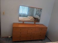 Front view of dresser with attached mirror, showing stain on top surface and drawer layout.