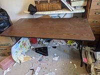 Top view of the rectangular wooden table top showing dark wood grain surface and foldable metal legs underneath.